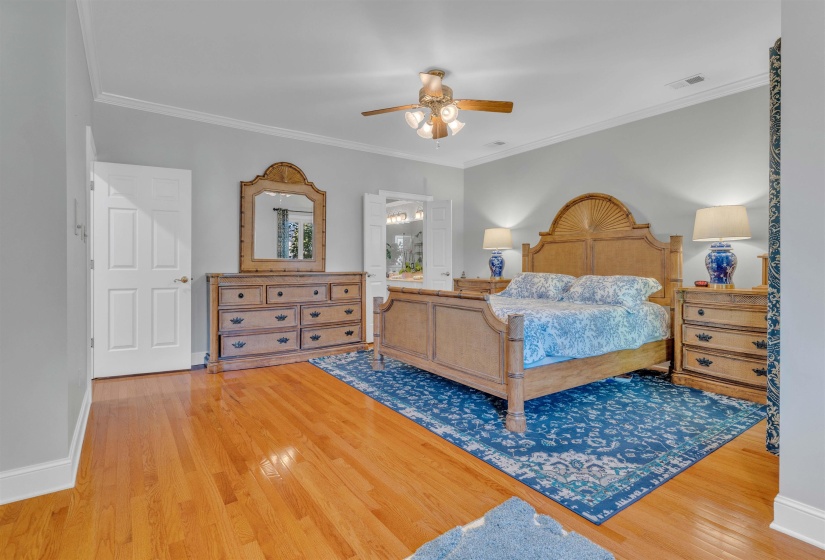 Spacious room featuring wood-finish flooring, crown molding, and a ceiling fan with integrated lighting