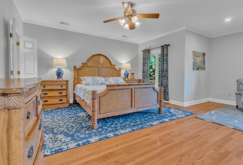 Spacious interior with wood-finish flooring, crown molding, and a ceiling fan with integrated lighting