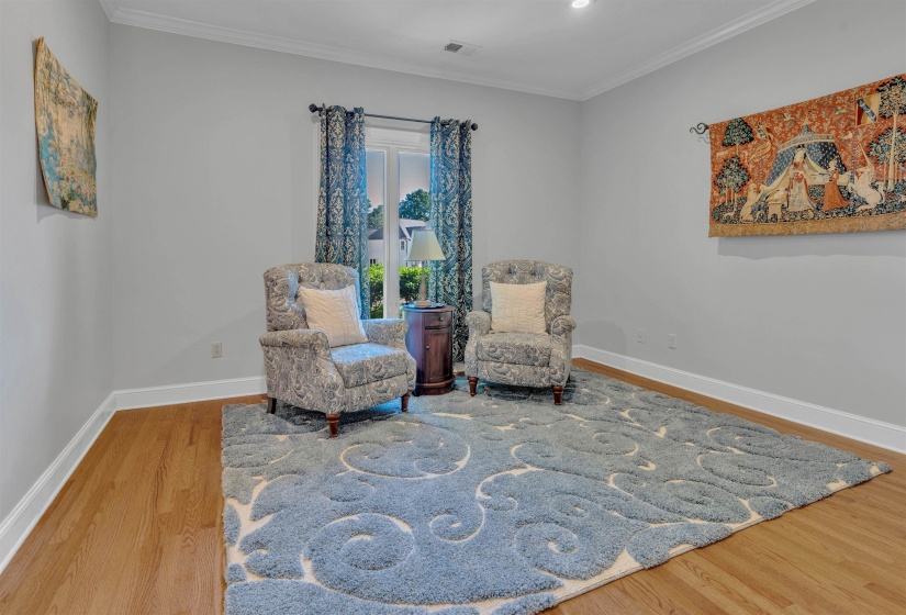 Neutral tone walls, crown molding, and wood-finish flooring