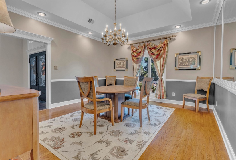 Hardwood flooring throughout, tray ceiling with recessed lighting, and a chandelier