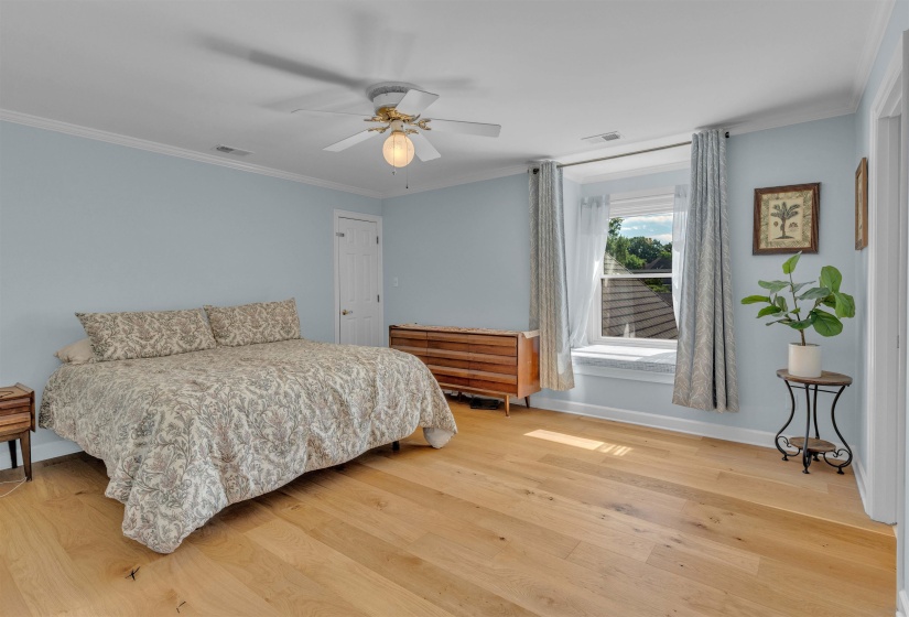 Bedroom featuring light wood-finish flooring, a ceiling fan with integrated lighting, and crown molding