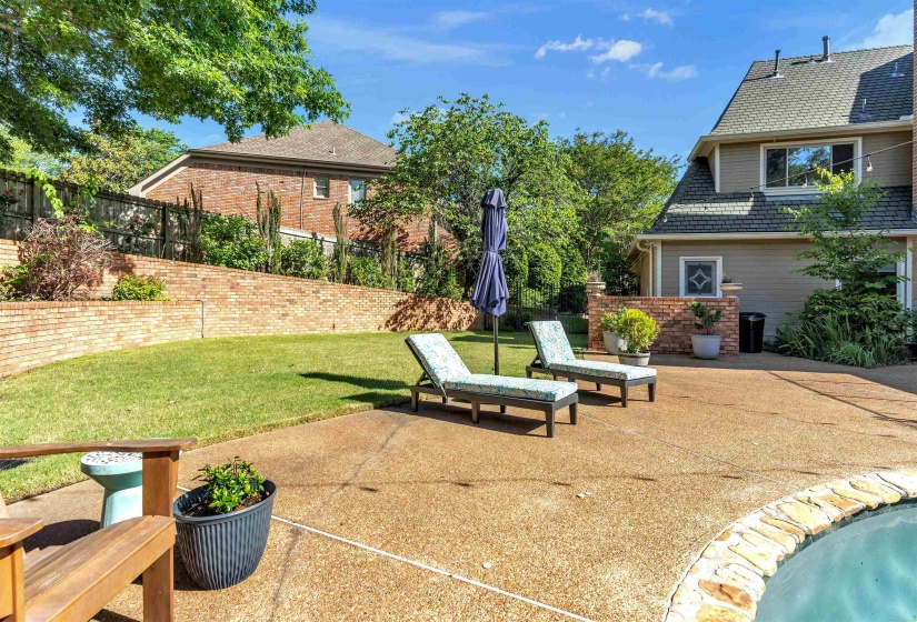 Expansive concrete patio surrounding a pool with natural stone coping