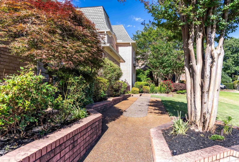 Landscaped entry featuring a brick retaining wall and a textured pathway