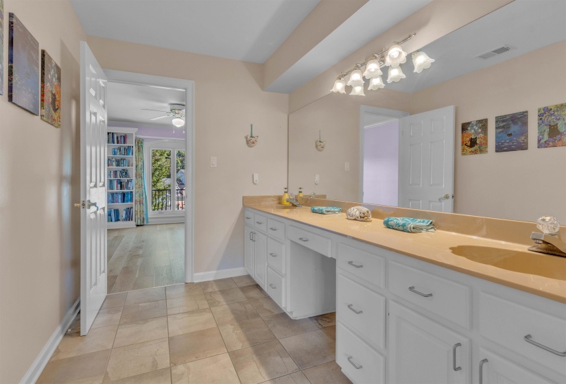 Vanity area featuring a long countertop, extensive white cabinetry, large wall-mounted mirror, and tile flooring