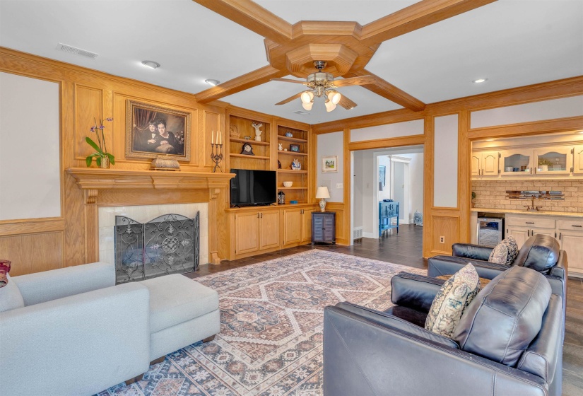 Living area featuring wood paneling, a wood-mantel fireplace with a metal screen, built-in cabinetry, recessed lighting, and a ceiling fan