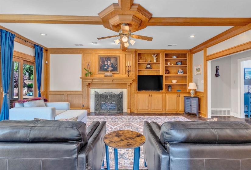 Living space featuring a wood-mantel fireplace with an ornate screen, integrated built-in shelving, and cabinetry