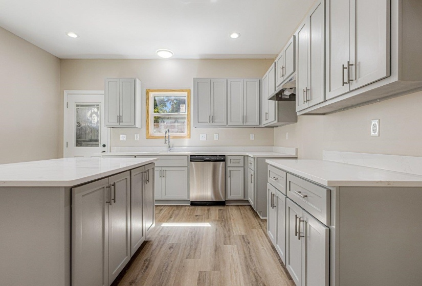 Kitchen with dishwasher, a kitchen island, light wood-style floors, recessed lighting, and gray cabinetry
