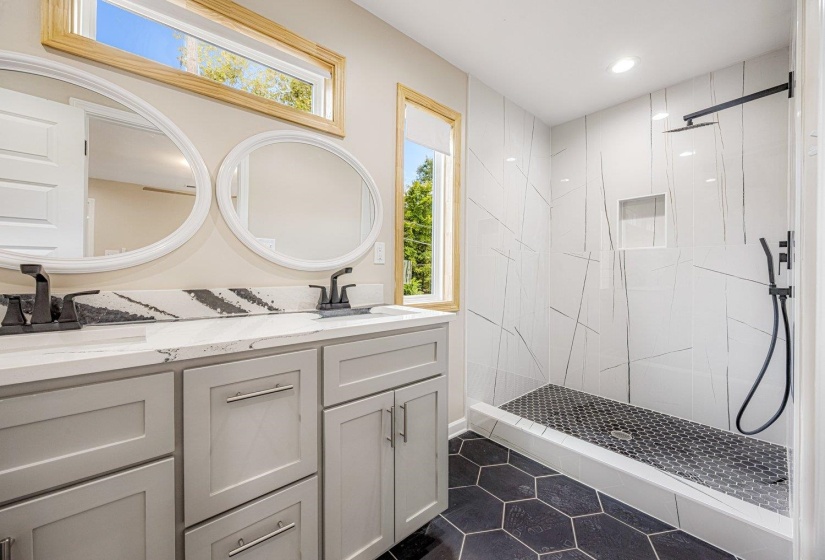 Full bathroom with a stall shower, double vanity, dark tile patterned flooring, and recessed lighting