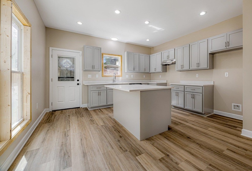 Kitchen featuring gray cabinets, recessed lighting, a center island, light wood-type flooring, and under cabinet range hood