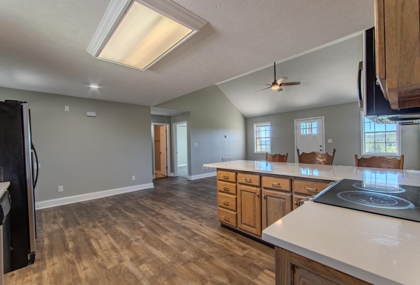 Kitchen featuring dark wood-style floors, plenty of natural light, appliances with stainless steel finishes, lofted ceiling, and a textured ceiling