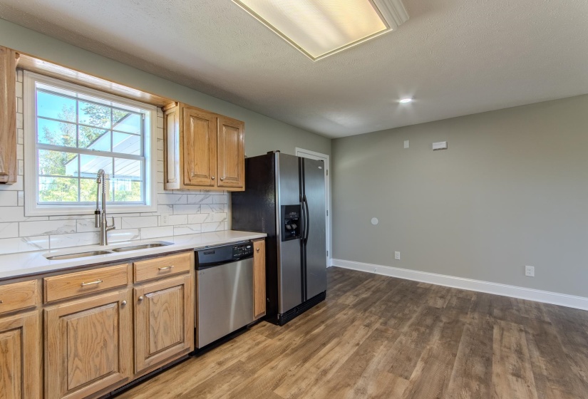 Kitchen with appliances with stainless steel finishes, dark wood-style floors, decorative backsplash, and light stone counters