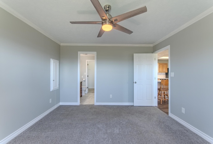 Unfurnished bedroom featuring carpet flooring, ornamental molding, and ceiling fan