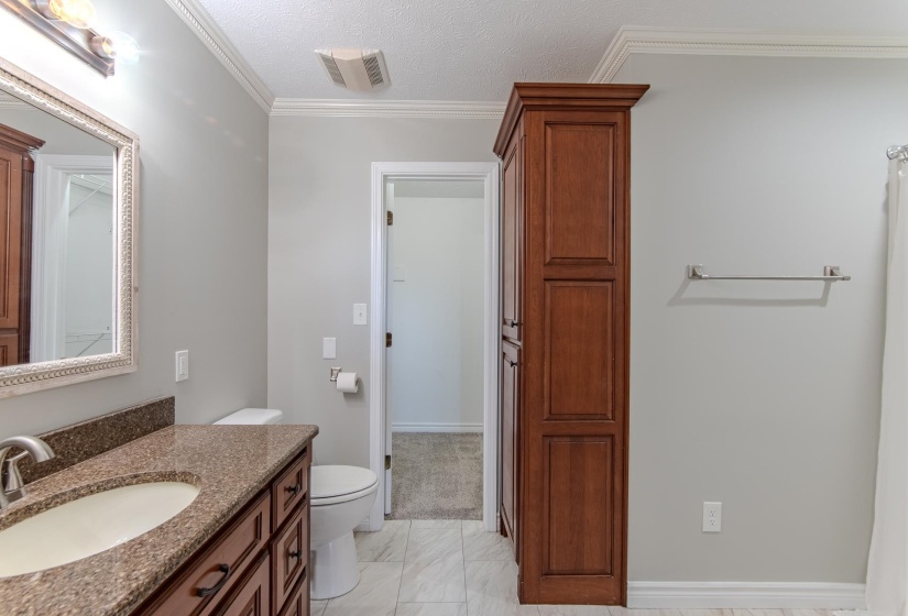 Bathroom with crown molding, a textured ceiling, vanity, and light marble finish flooring