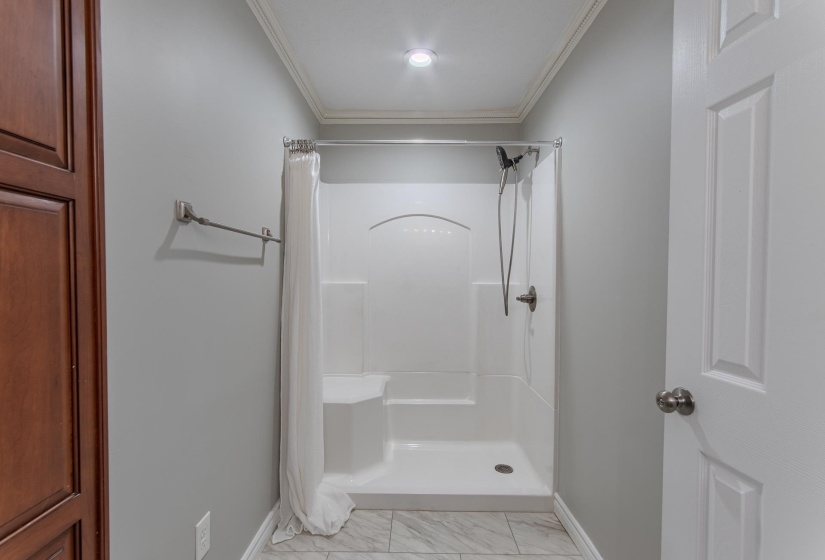 Full bathroom with a shower stall, ornamental molding, and light marble finish floors
