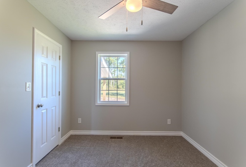 Carpeted empty room featuring a textured ceiling and ceiling fan