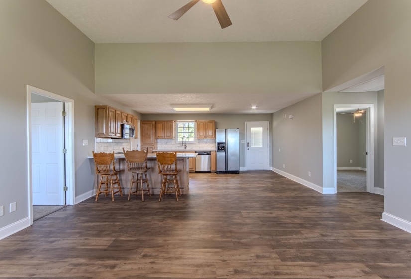 Kitchen with a ceiling fan, brown cabinets, stainless steel appliances, light countertops, and dark wood-type flooring