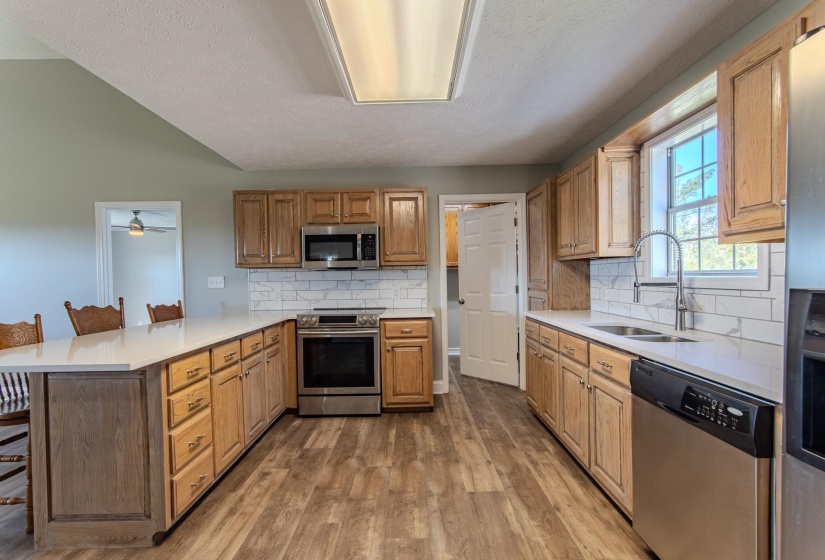 Kitchen featuring a kitchen breakfast bar, a peninsula, appliances with stainless steel finishes, backsplash, and light wood finished floors