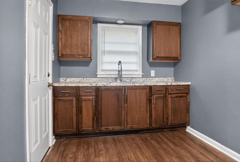 Kitchen featuring a textured wall, dark wood-style floors, and light stone countertops