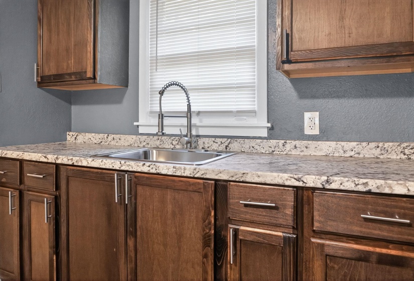 Kitchen featuring a textured wall, light countertops, and dark brown cabinets