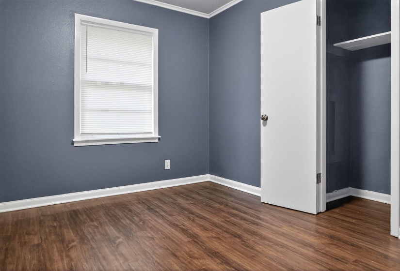 Unfurnished bedroom featuring ornamental molding and dark wood-type flooring