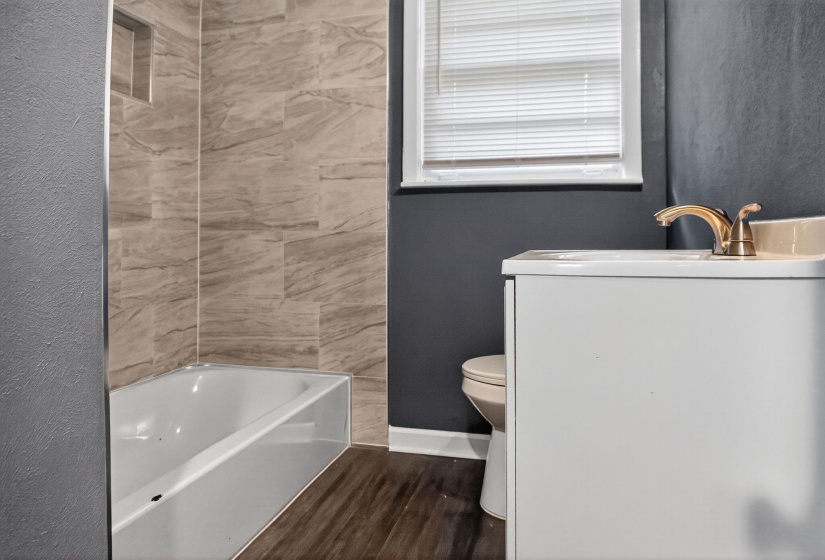 Full bath with vanity, dark wood-style flooring, a textured wall, and tub / shower combination