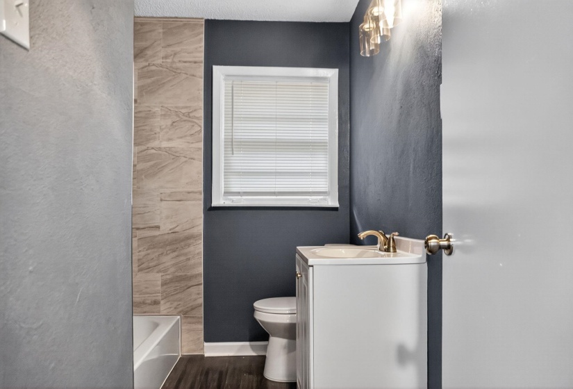 Full bathroom with vanity, a textured wall, dark wood-type flooring, and bathtub / shower combination