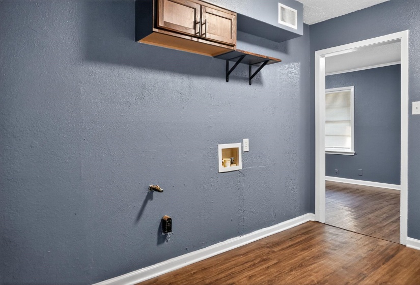 Washroom with a textured wall, wood finished floors, and hookup for a washing machine