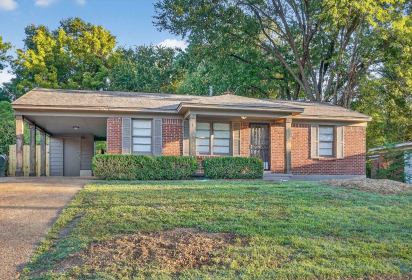 Single story home with an attached carport, brick siding, a front yard, and driveway