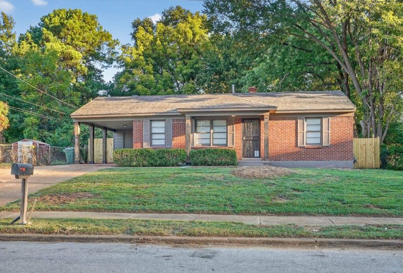 View of front of property featuring a carport, a chimney, concrete driveway, and brick siding