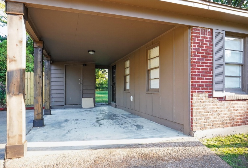 Entrance to property featuring brick siding, an attached carport, and covered porch