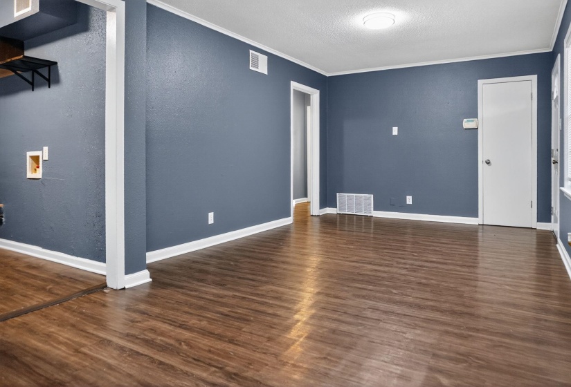 Unfurnished living room featuring ornamental molding, dark wood finished floors, a textured ceiling, and a textured wall