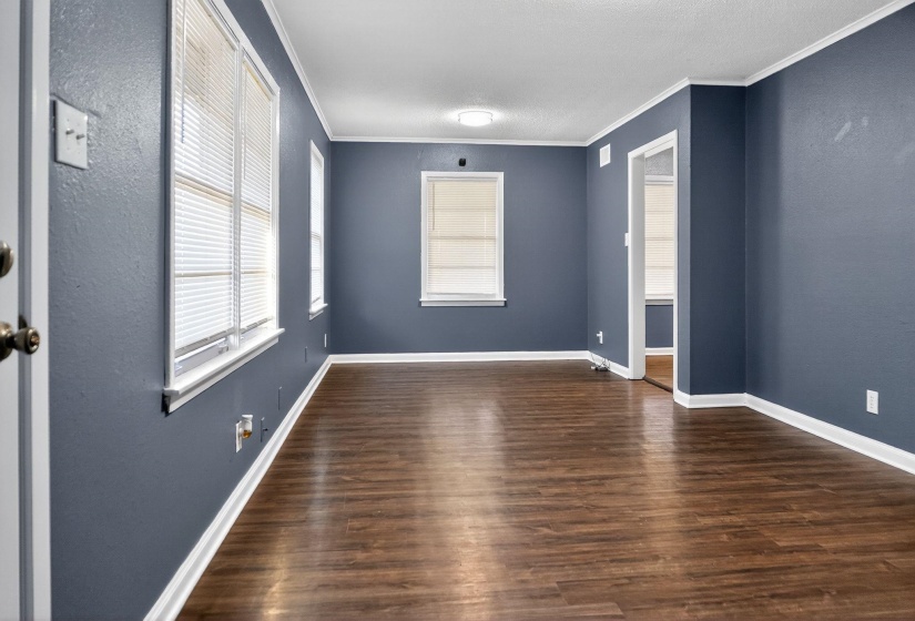 Empty room featuring ornamental molding, dark wood-type flooring, a textured wall, and a textured ceiling