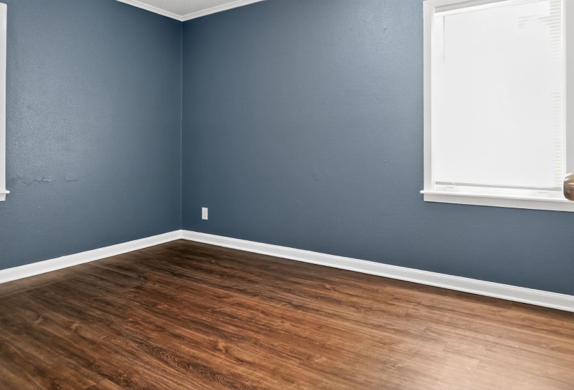 Spare room with dark wood-style floors, crown molding, and a textured wall