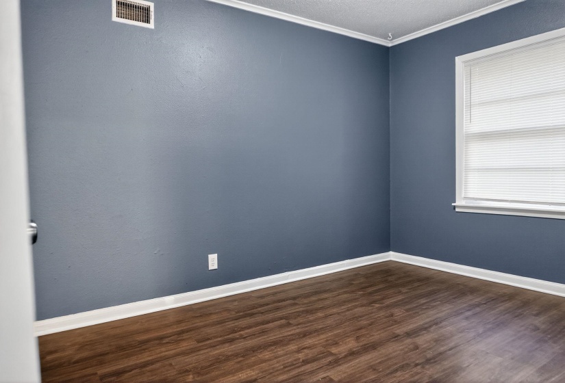 Empty room featuring dark wood finished floors, crown molding, and a textured ceiling
