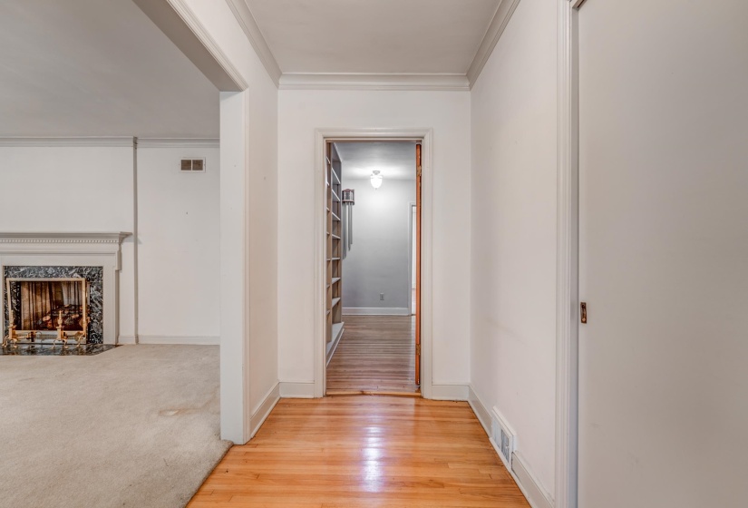 Hallway with crown molding, light wood-style floors, and light colored carpet
