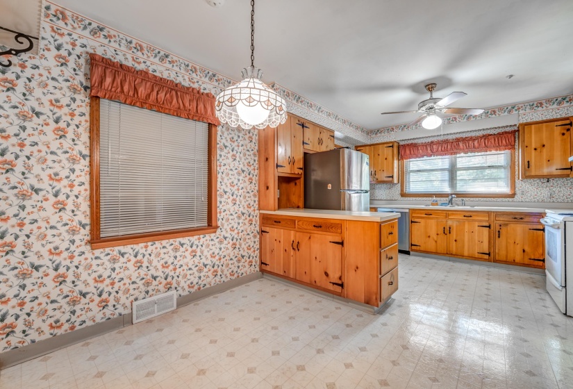 Kitchen featuring a peninsula, light countertops, pendant lighting, light floors, and appliances with stainless steel finishes