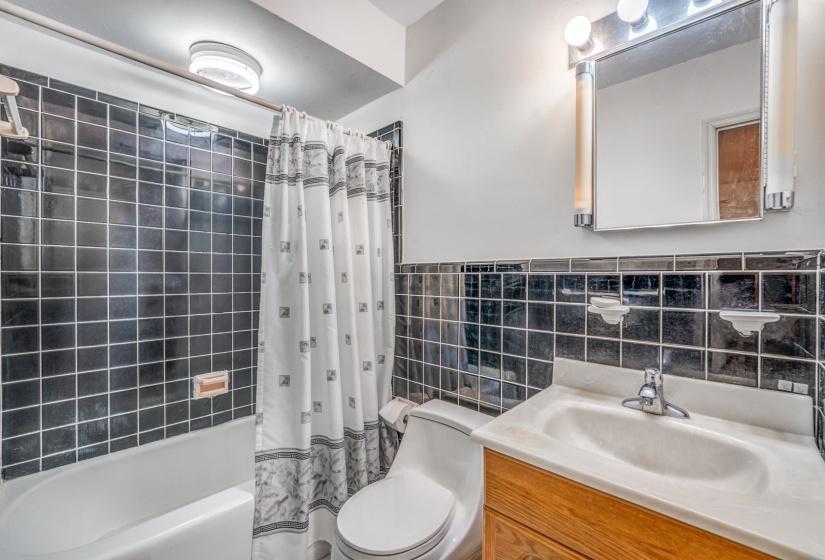 Full bath featuring shower / bathtub combination with curtain, tile walls, and vanity