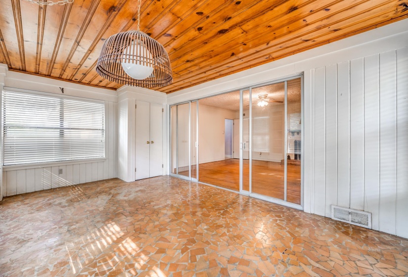Unfurnished bedroom with a closet, wood ceiling, wooden walls, and stone floors