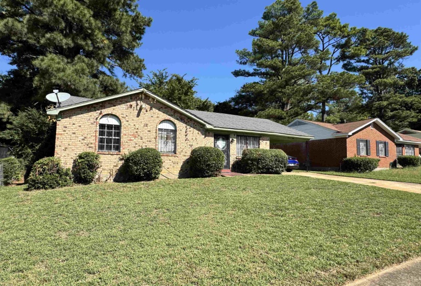 Ranch-style house featuring brick siding, a front lawn, driveway, and an attached carport