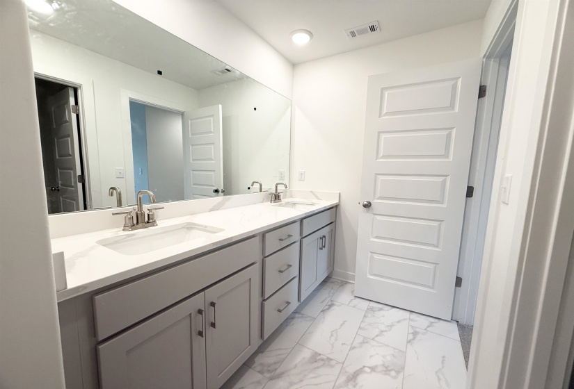 Full bath with double vanity and marble finish floors