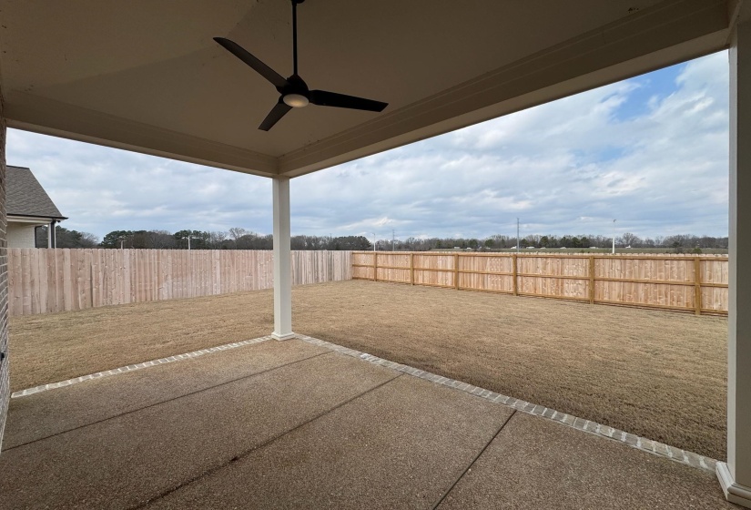 Fenced backyard with a ceiling fan and a patio