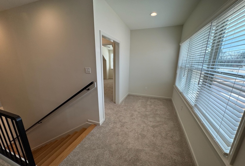 Hall featuring an upstairs landing, light carpet, and recessed lighting