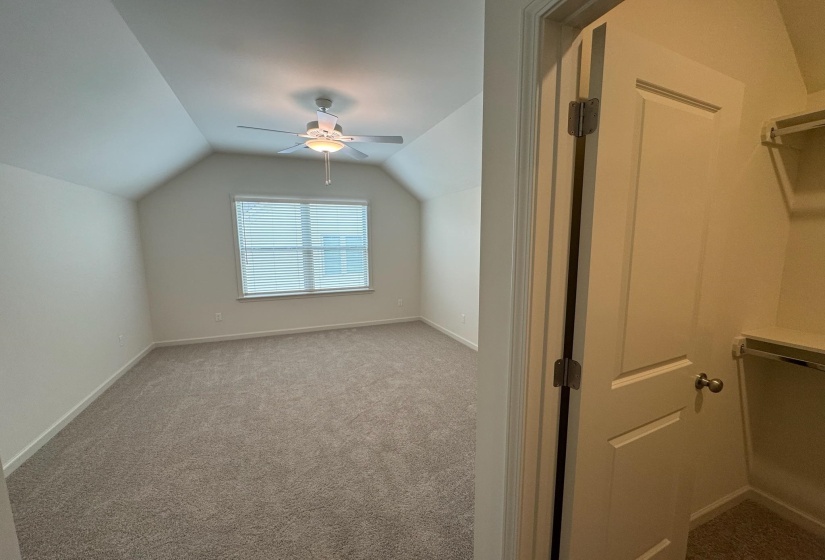 Additional living space featuring dark carpet and a ceiling fan