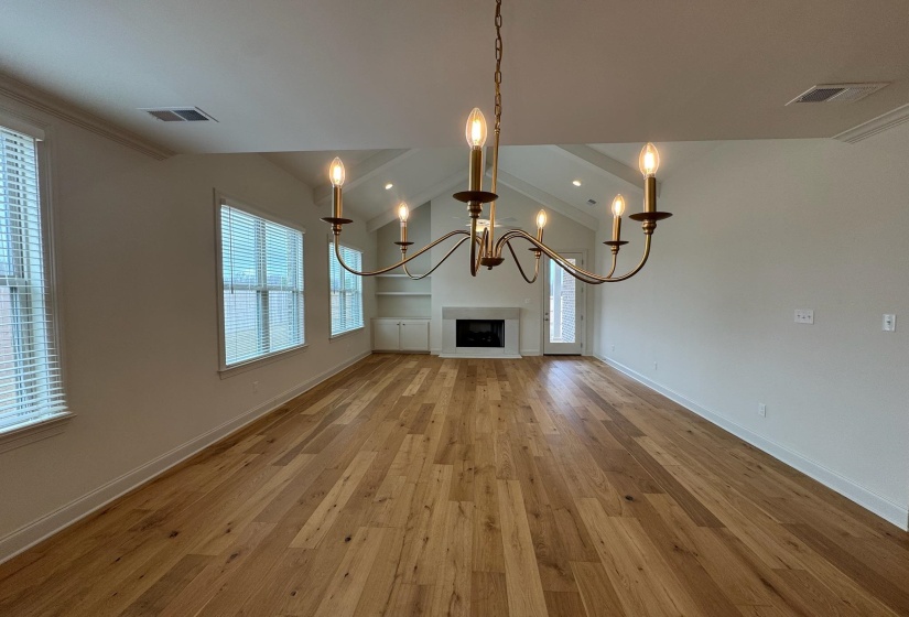 Unfurnished living room with lofted ceiling, light wood-type flooring, a chandelier, and a fireplace