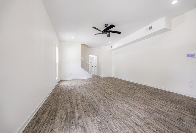Unfurnished room with wood finished floors, recessed lighting, a ceiling fan, and stairs