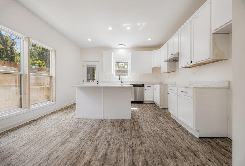 Kitchen featuring recessed lighting, a kitchen island, white cabinetry, light countertops, and light wood-style floors