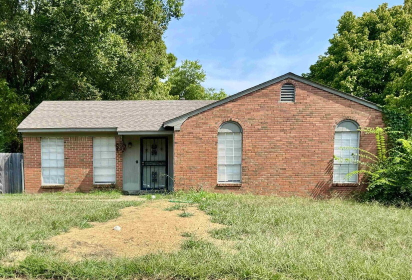 Ranch-style house with brick siding, roof with shingles, and a front lawn