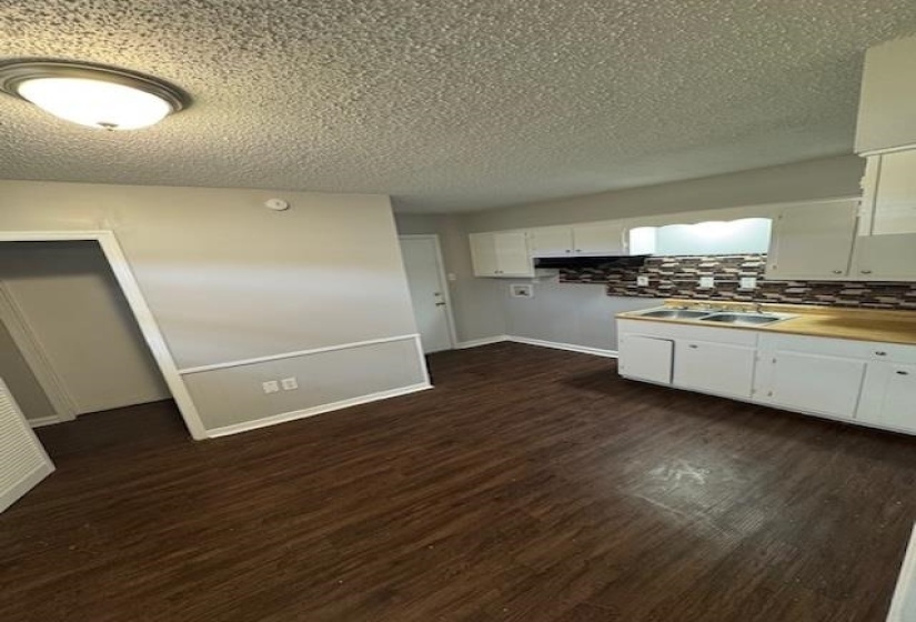 Kitchen featuring white cabinets, decorative backsplash, dark wood finished floors, and a textured ceiling