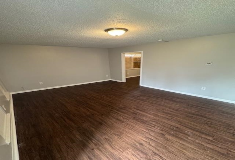 Empty room featuring dark wood-style flooring and a textured ceiling