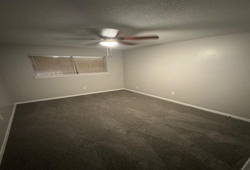 Spare room with a textured ceiling, dark carpet, and a ceiling fan